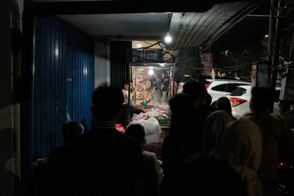Grupo de pessoas do lado de fora de um edifício à noite na Indonésia